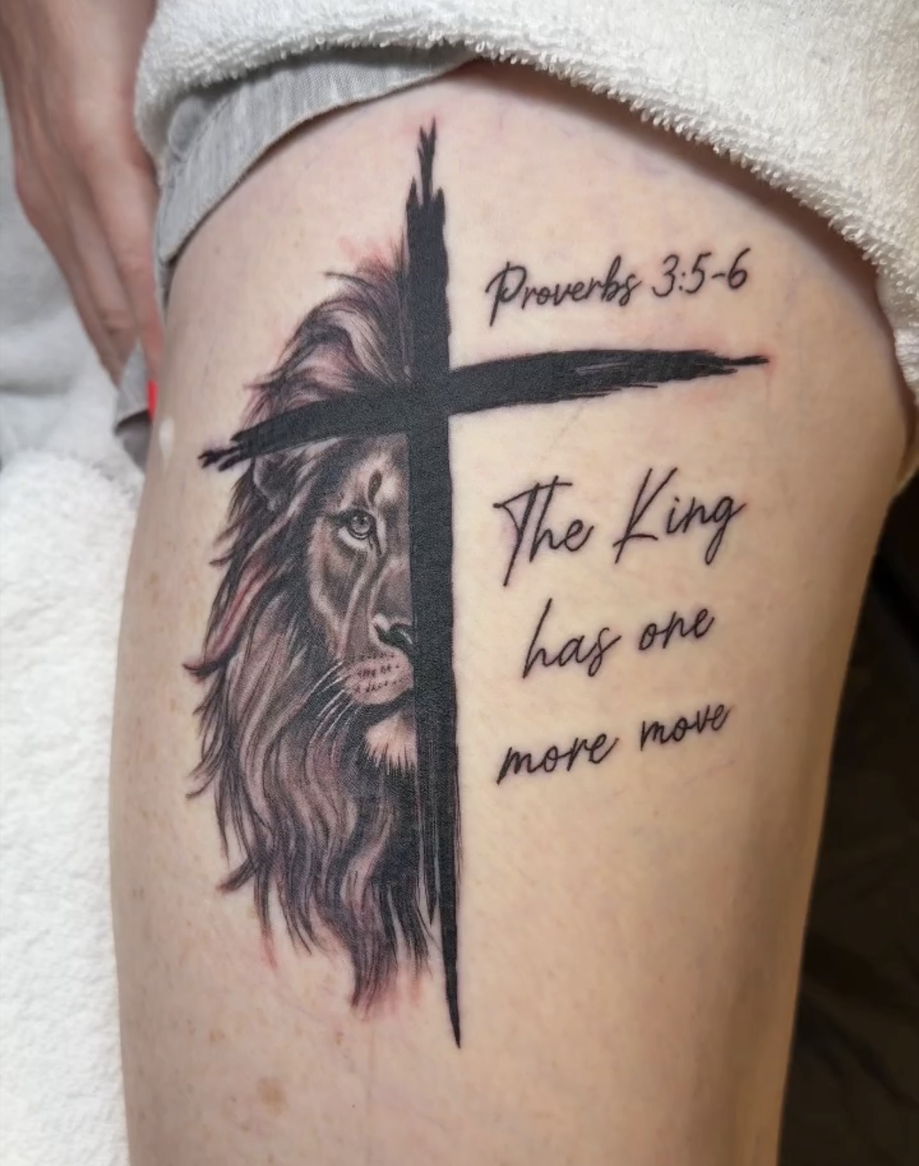 A lion portrait beside a bold cross, with Proverbs 3:5–6 and the words “The King has one more move.” Tattoo work by Joseph Rojas.